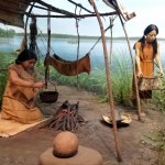 diorama of a woman cooking over a fire and another woman walking with a birch basket