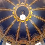 a lighted globe chandelier suspended from the center of a dark-blue dome