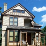a light-brown house with dark brown accents and a porch in front