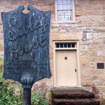 weathered old slate sign for the Sibley House in front of a stone building