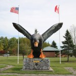 Large black duck statue that appears to be swooping toward the camera