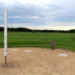 A tall white post next to three concrete plaques on the ground, with a brown sign with instructions