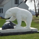 a polar bear statue with its paw on a seal